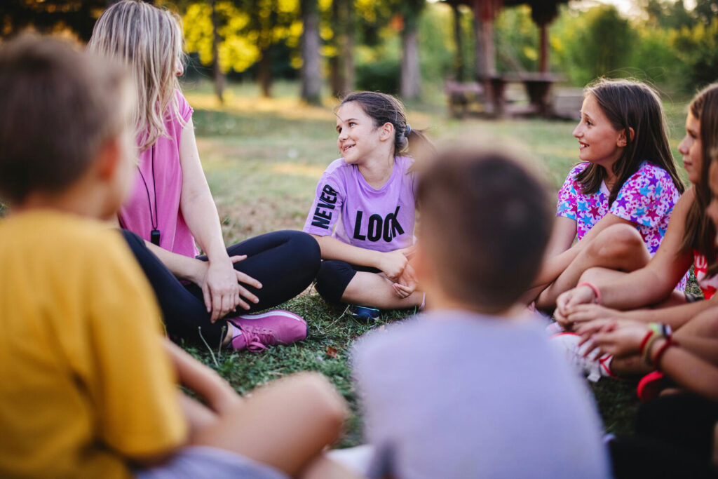 Camp counsellor leading outdoor group activity with children
