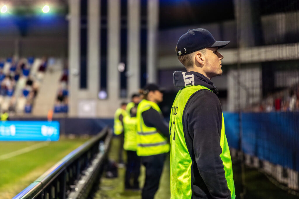 Event security staff monitoring crowd at night football match