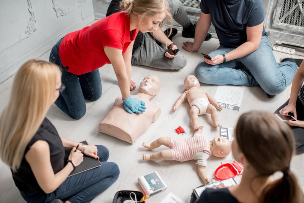 First aid instructor demonstrating CPR technique during a group training session