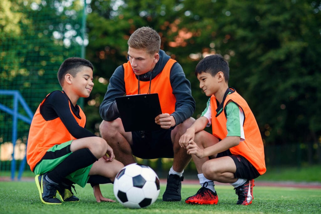 Youth football coach reviewing tactics with young players