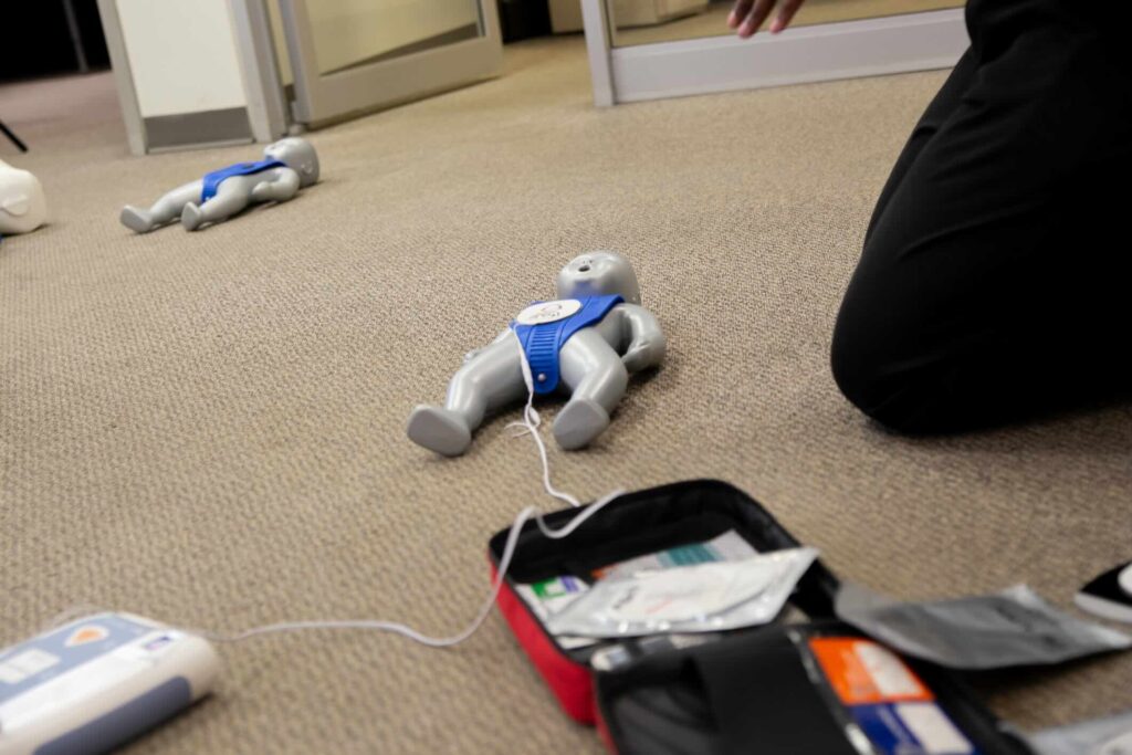 Staff practicing first aid cpr with their fingers and AED machine