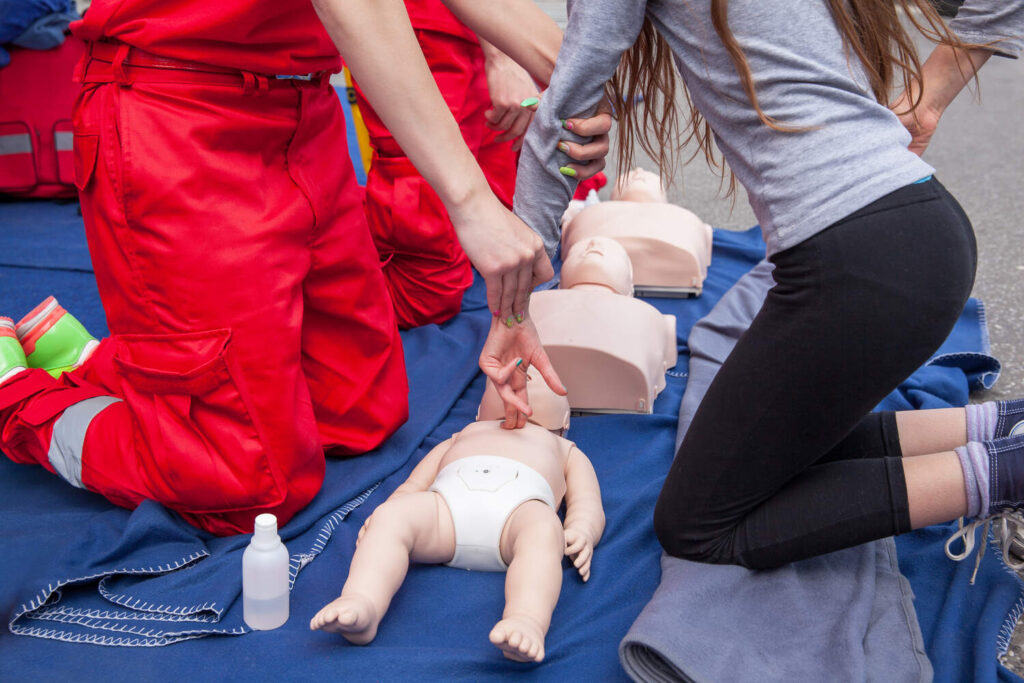Two trainees practicing infant CPR on training manikins